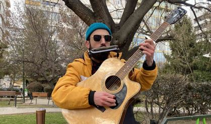 Aynı anda hem mızıka hem de gitar çalıyor